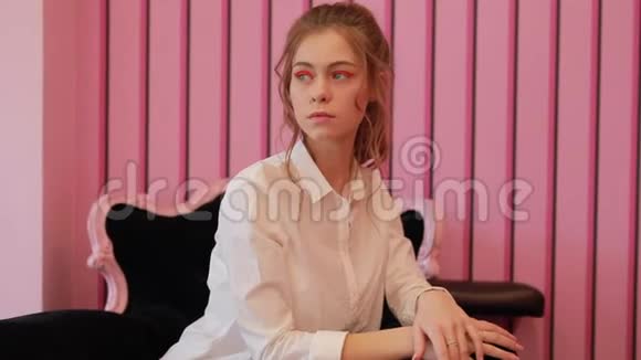 年轻模特在粉色工作室的椅子上摆姿势视频的预览图