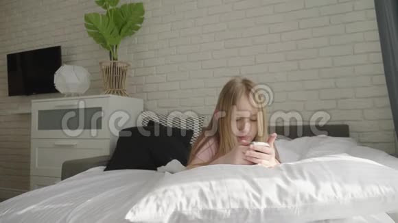 小女孩躺在床上看着她的智能手机视频的预览图