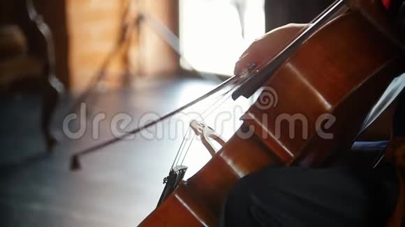一位年轻女子演奏大提琴琴弓沿着琴弦平稳地走着视频的预览图