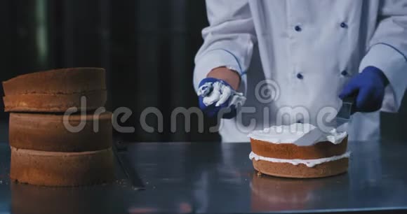 这个面包师正在用他干净的手握住这把大铲继续把奶油顺利地铺在上面视频的预览图