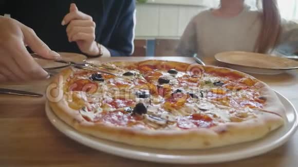 女人想在餐馆里吃一片热比萨饼一家人吃真正的意大利披萨玩得开心生活方式和视频的预览图
