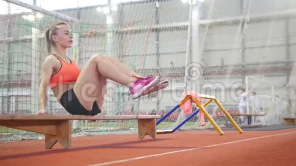 年轻的运动女子用长凳训练腹肌视频的预览图