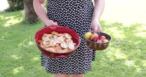 花园里的女人手里拿着两碗李子视频的预览图