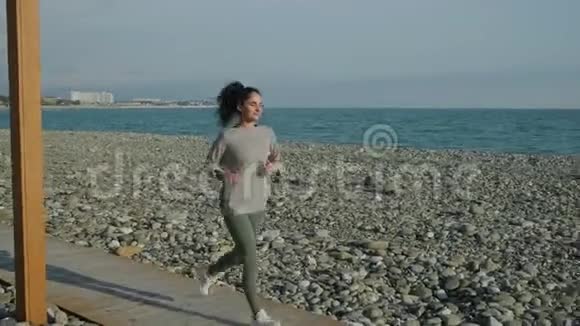 阳光明媚的一天少女独自在海边慢跑视频的预览图