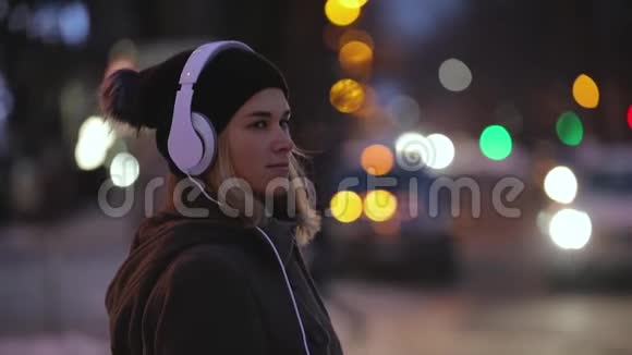 戴着耳机的独身女子准备过马路城市之夜视频的预览图