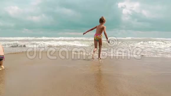 小女孩沿着沙质的海边奔跑享受和享受海浪来到海滩愉快的假期视频的预览图