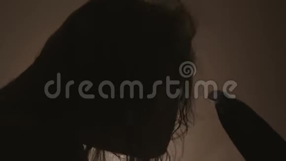 洗完头后用吹风机吹干头发的女人的剪影视频的预览图