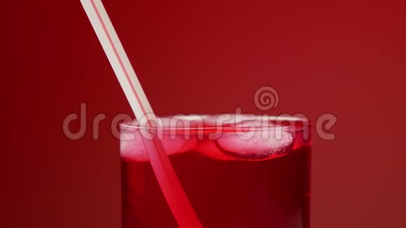有人喝着带冰的红色苏打水把吸管扔了红色背景慢动作视频的预览图