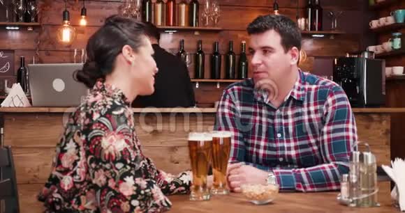 在时尚的老式酒吧餐厅喝啤酒的情侣们尽情狂欢视频的预览图