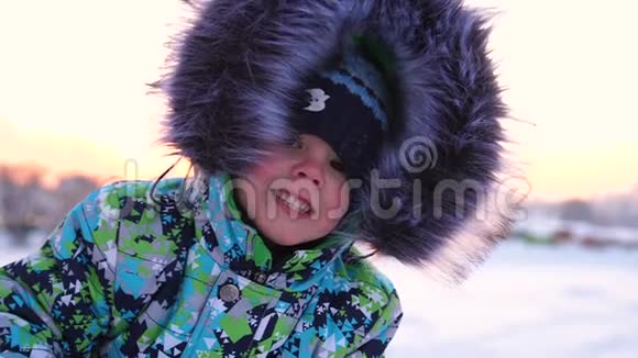 一个小孩子在冬天的公园里散步在白色蓬松的雪上玩耍和微笑的婴儿面的特写积极休息视频的预览图