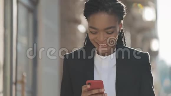 微笑着迷人的黑人商务女性使用智能手机在市中心行走黑色时尚可怕的家伙非洲裔视频的预览图