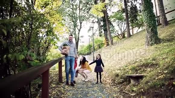 秋天有孩子在公园散步的一个小家庭慢动作视频的预览图