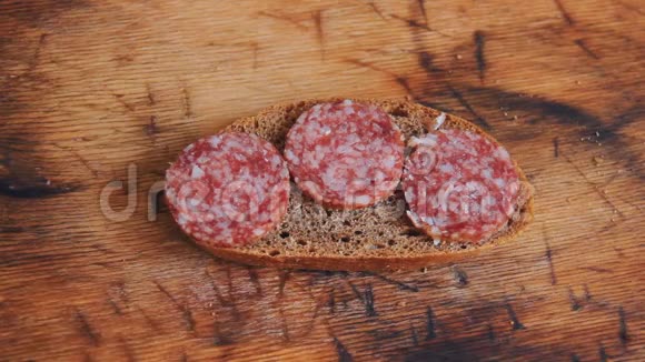一个男人手拿一个三明治和肉片腊肠作为零食或早餐一片黑面包视频的预览图