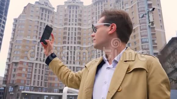 在现代建筑背景下戴眼镜的高加索人拍摄城市的画面视频的预览图