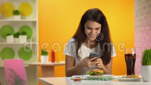坐在快餐店的女学生在智能手机上打字视频的预览图