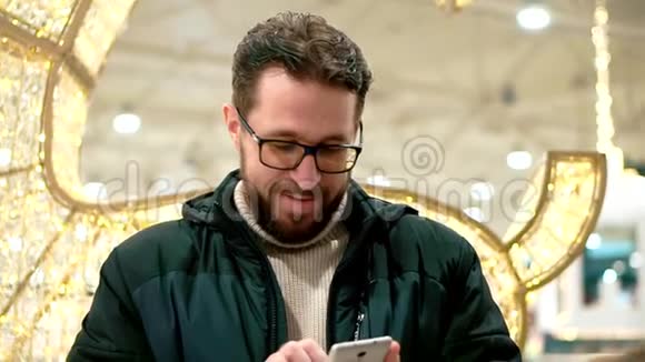 长胡子的男人戴着眼镜看着智能手机读着留言人们经过视频的预览图