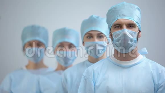 戴口罩和制服看镜头的专业外科医生团队医院工作视频的预览图