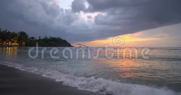 美丽的海景绿色的海岸和孤独的小船在海水上飘扬平静的海洋上方多云的夜空视频的预览图