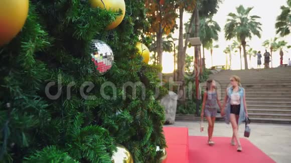 在热带城市圣诞树的背景下快乐的妈妈和女儿新年旅行的概念视频的预览图
