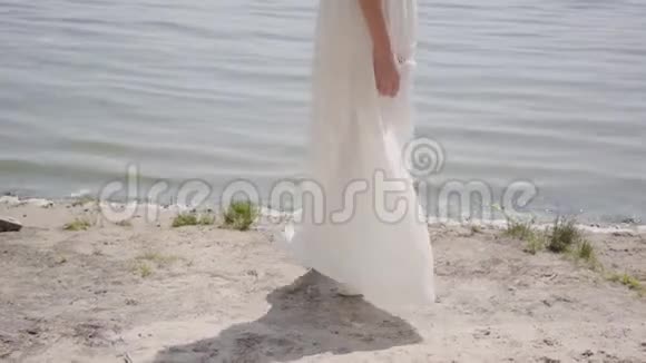 未被认出的女孩穿着一件白色的夏季时装长裙站在河边户外休闲美女视频的预览图