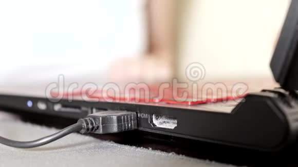 女士将黑色USB电缆插入笔记本电脑并开始键盘输入关闭视频的预览图