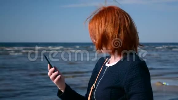商务女性从沙滩上的手提包里拿出手机视频的预览图