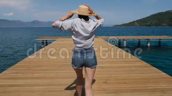 穿着帽子和短裤走在码头上的年轻性感女孩视频的预览图