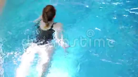 穿着黑色泳衣的年轻女孩在游泳池里游泳视频的预览图