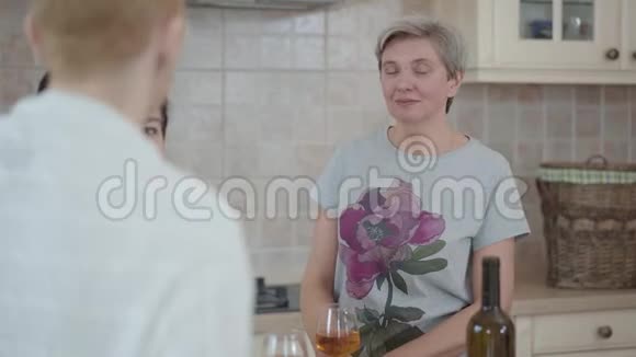 三个成熟的女人在厨房里和桌上的酒聊天一位女士一边打手势视频的预览图