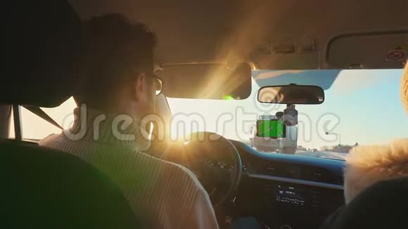 冬天在阳光明媚的公路上开车的人智能手机有一个绿色屏幕连接到挡风玻璃卡车视频的预览图