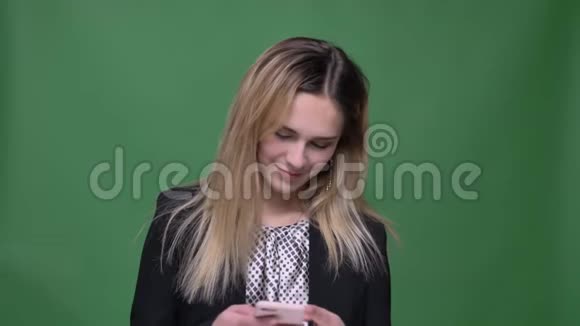 年轻迷人的潮人白种人女性的特写镜头用手机看镜头用背景微笑视频的预览图