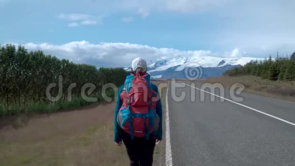 带背包的女旅行者在柏油路上视频的预览图