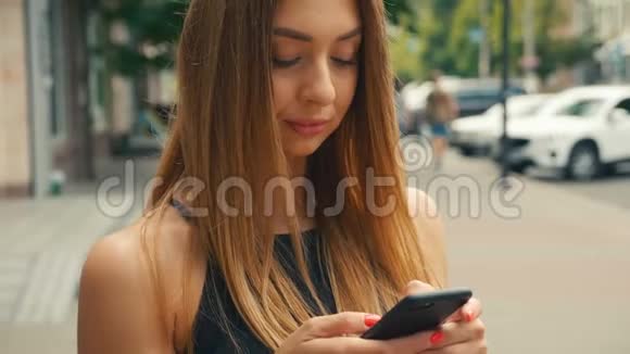 美女在手机上打字背景是街上行人棕色头发的女人看着视频的预览图