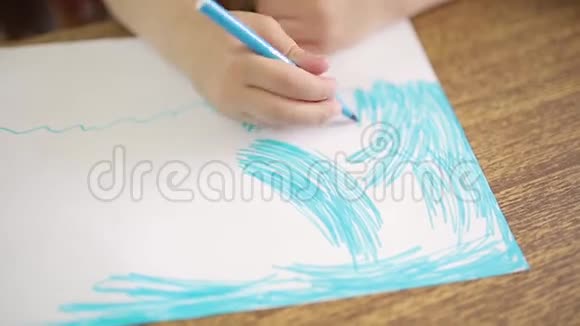 女孩用蓝色的毡尖笔画在白色的纸上画出海洋或海洋的艺术图画一个女孩的手视频的预览图