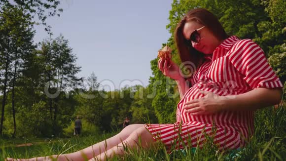 孕妇手牵着手在公园里吃三明治抚摸肚子中弹视频的预览图