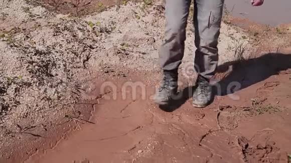 在沙漠地区泥泞的地面上行走的流浪汉的腿的特写视频的预览图
