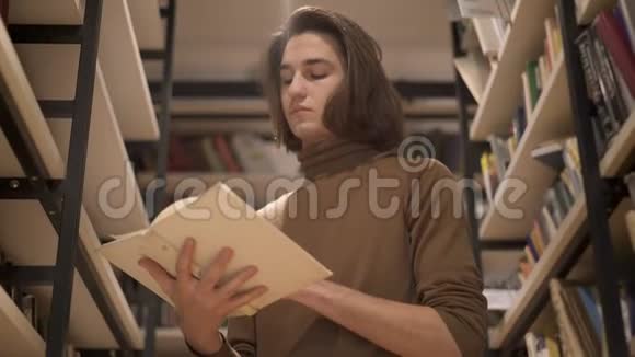 在书架之间翻书的年轻人视频的预览图