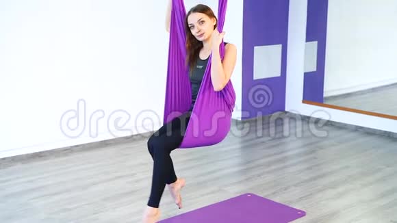 一位年轻女子在吊床上练习反重力瑜伽的肖像视频的预览图