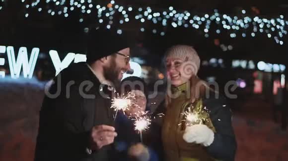 家人庆祝新年父亲母亲和儿子笑着高兴地跳在孟加拉火的手中在街上视频的预览图