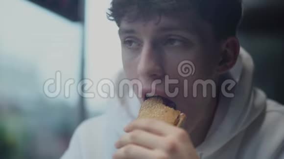 在快餐店吃三明治和思考的年轻有魅力的杀手画像视频的预览图