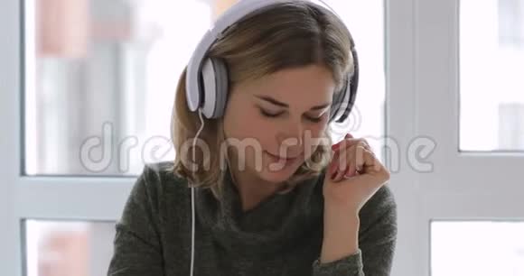 女人在家放松带着茶和耳机的好音乐视频的预览图