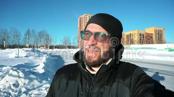 冬天有胡子戴眼镜的男人在街上背景下自拍很冷视频的预览图