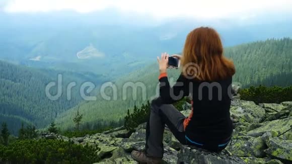 少女徒步旅行者在山顶上拍照视频的预览图