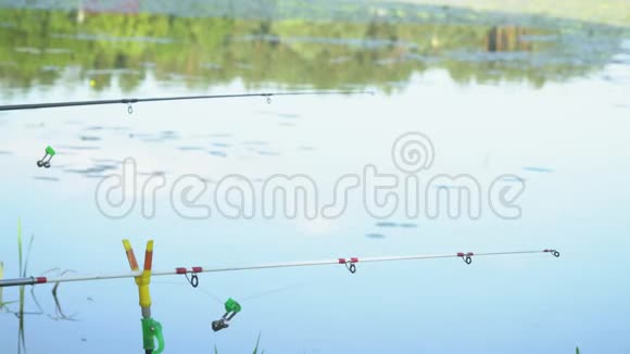 夏日湖上两根钓鱼竿专业钓竿等待水河上的叮咬视频的预览图