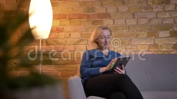 用平板电脑拍摄高加索大龄女性的特写镜头并在室内用绿色屏幕拍摄微笑视频的预览图