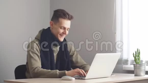 年轻人微笑着看着家里的笔记本电脑视频的预览图