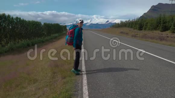 带背包的女旅行者在柏油路上视频的预览图