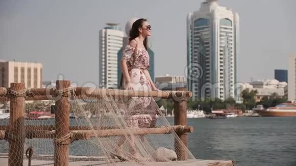 穿着裙子的女孩在码头上对着摩天大楼自拍视频的预览图