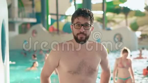 一个戴眼镜的留胡子的人在室内的水上公园里休息视频的预览图