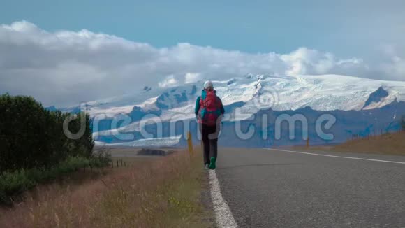 带背包的女旅行者在柏油路上视频的预览图